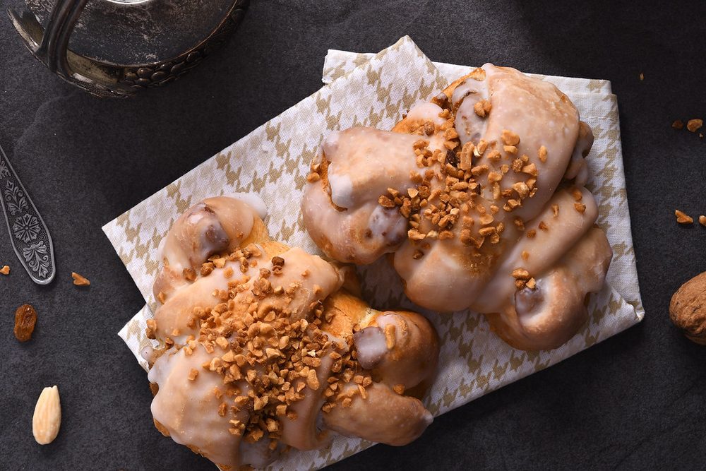 Glazed pastries topped with toffee pieces on parchment